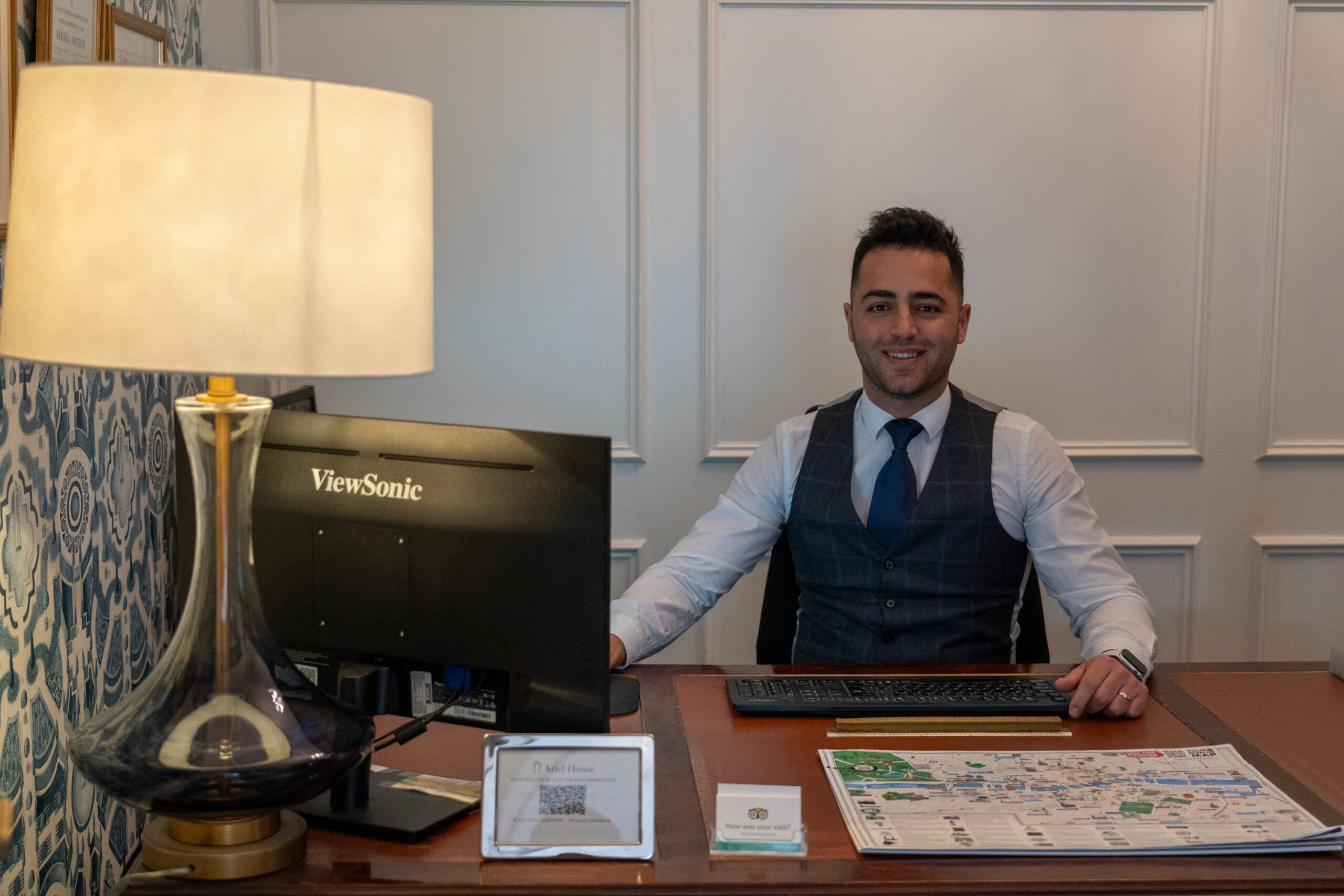 A friendly staff member sitting at reception desk at Ariel House Dublin
