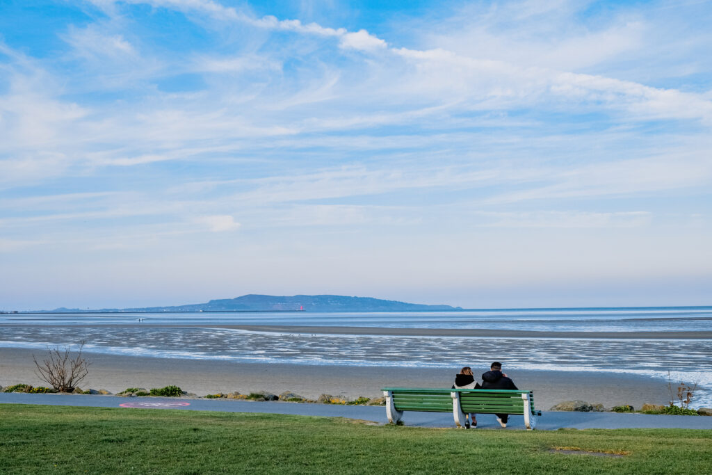sandymount-strand-dublin-walks-near-ariel-house Couple sitting on bench overlooking Sandymount Strand near Ariel House Dublin