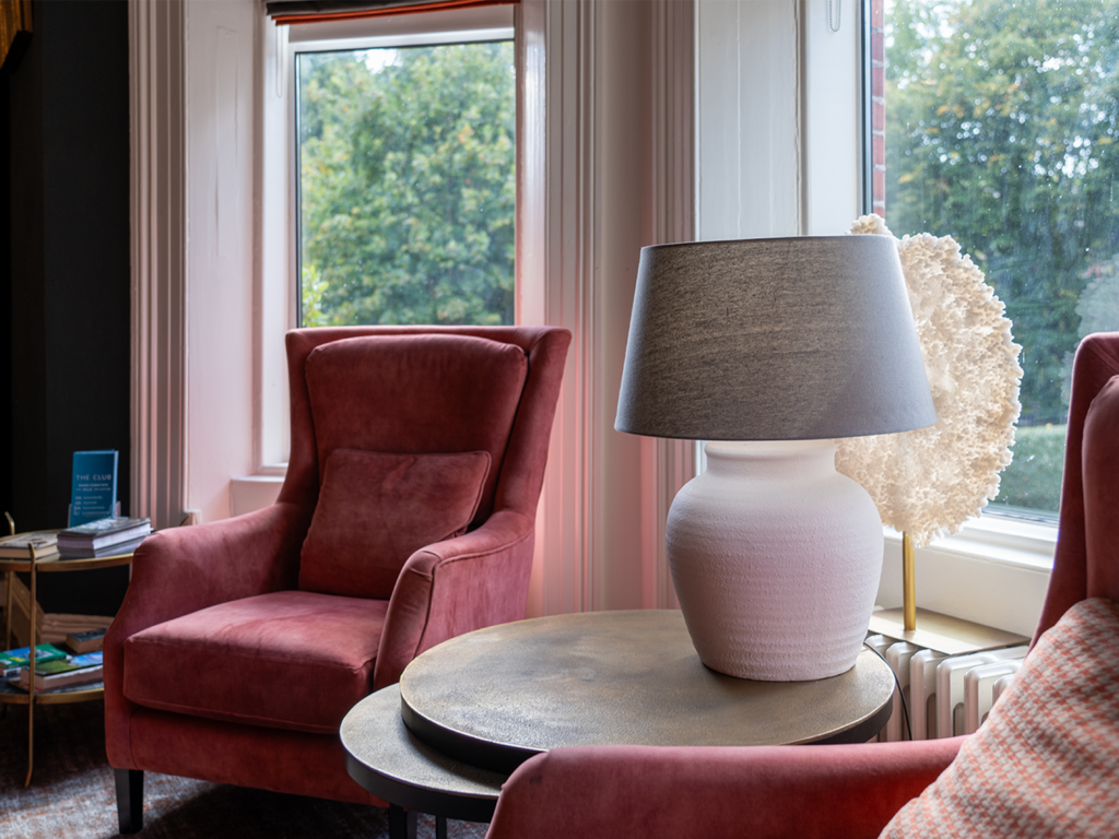 Drawing room at Ariel House Dublin with comfortable armchairs, sofas and books to relax in a quiet, warm-lighted setting.