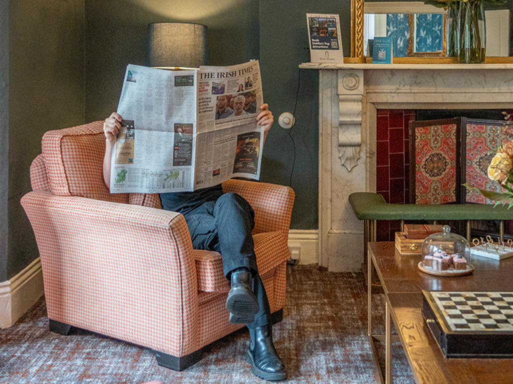 Ariel-Haus-Salon-Zeitung Ein Gast entspannt sich im Sessel und liest Zeitung im Salon des Ariel-Hauses