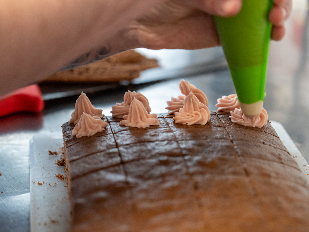Chef piping icing onto homemade cake at Ariel House Dublin kitchen