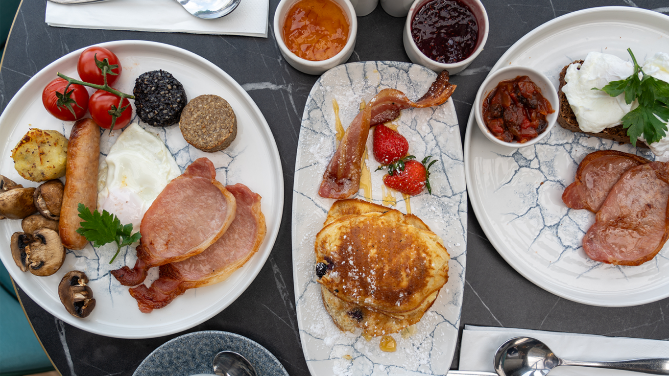 From left to the right: full-irish breakfast plate, pancakes with bacon, maple syrup and strawberries and poached eggs with bacon and veggies.