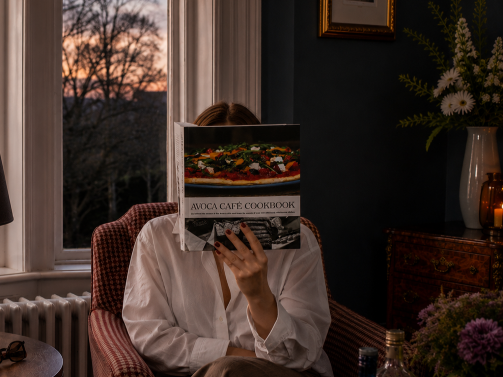 relaxing-stay-ariel-house-ballsbridge-dublin-autumn-winter Guest relaxing with a cookbook by the window at Ariel House in Ballsbridge, Dublin.